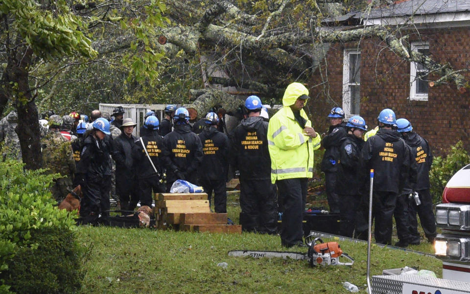 Rescue workers, police and fire department members wait to remove the bodies of a mother and child who were killed by a falling tree as Hurricane Florence made landfall in Wilmington, N.C. Friday Sept. 14, 2018. The father was transported to the hospital with serious injuries. (Chuck Liddy/The News & Observer via AP)