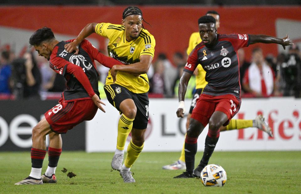 Sep 18, 2024; Toronto, Ontario, CAN; Columbus Crew forward Jacen Russell-Rowe (19) moves the ball past Toronto FC midfielder Derrick Etienne Jr. (11) and defender Raoul Petretta (28) in the first half at BMO Field. Mandatory Credit: Dan Hamilton-Imagn Images