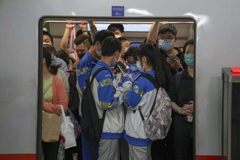 Students browsing their smartphones crowd with commuters inside a subway train in Beijing Tuesday, Sept. 14, 2021. China has set new rules limiting the amount of time kids can spend playing online games. (AP Photo/Andy Wong)