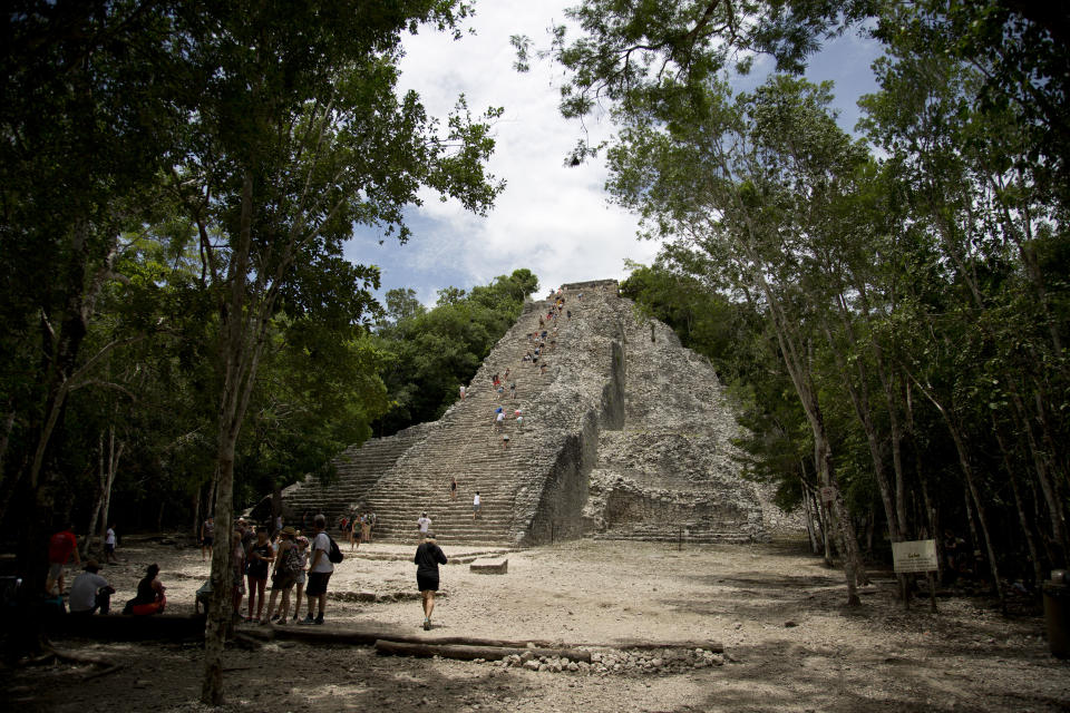 In this Aug. 1, 2018 photo, tourists climb the pyramid at the archeological site of Coba on Mexico's Yucatan Peninsula. Mexico's president-elect Andres Manuel Lopez Obrador wants to bring tourism revenues to more remote and forgotten stretches of Mexico, like Coba, with a train running from Cancun to Palenque, Chiapas. (AP Photo/Eduardo Verdugo)