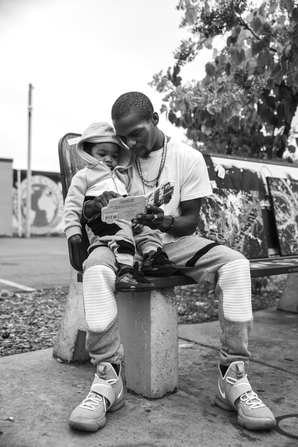 Twan reads a book to his son that they got from the Metro Library, a bus shelter that was turned into a free library with books for children. George Floyd Square, Minneapolis, Minnesota, September 26, 2020. (Photo: Patience Zalanga)