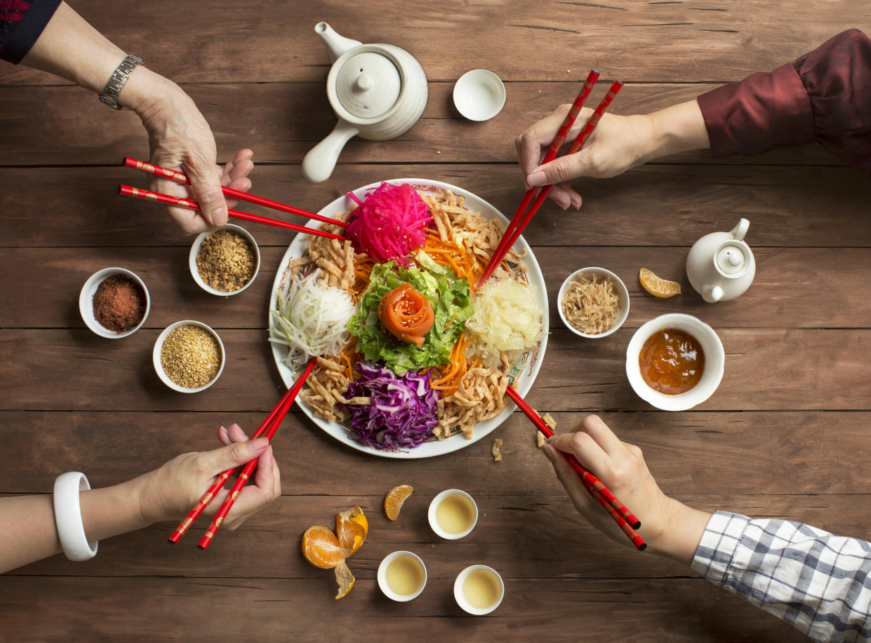 Yusheng, yee sang or yuu sahng 魚生; or Prosperity Toss, is a popular dish to served during chinese new year period especially in Malaysia and Singapore region. This is a Cantonese-style raw fish salad mixed with colourful shredded vegetables, pickles served with variety of sauces, nuts and herbs. Yusheng is a symbol of abundance, prosperity and vitality. Hands of family members lifting food.