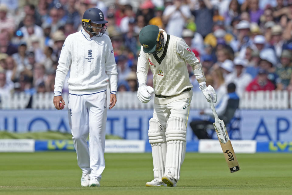 England's Joe Root, left, walks to look after Australia's Nathan Lyon, right, who reacts in pain during the fourth day of the second Ashes Test match between England and Australia, at Lord's cricket ground in London, Saturday, July 1, 2023. (AP Photo/Kirsty Wigglesworth)