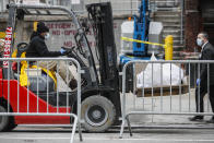 Bodies wrapped in plastic are loaded on to a refrigerated container truck operating as a makeshift morgue while being handled by medical workers wearing personal protective equipment due to COVID-19 concerns, Tuesday, March 31, 2020, at Brooklyn Hospital Center in the Brooklyn borough of New York. The new coronavirus causes mild or moderate symptoms for most people, but for some, especially older adults and people with existing health problems, it can cause more severe illness or death. (AP Photo/John Minchillo)