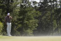 Tiger Woods trata de protegerse del viento en el green del hoyo 18 el viernes 12 de abril de 2024, en el Masters de Augusta, Georgia (AP Foto/Ashley Landis)