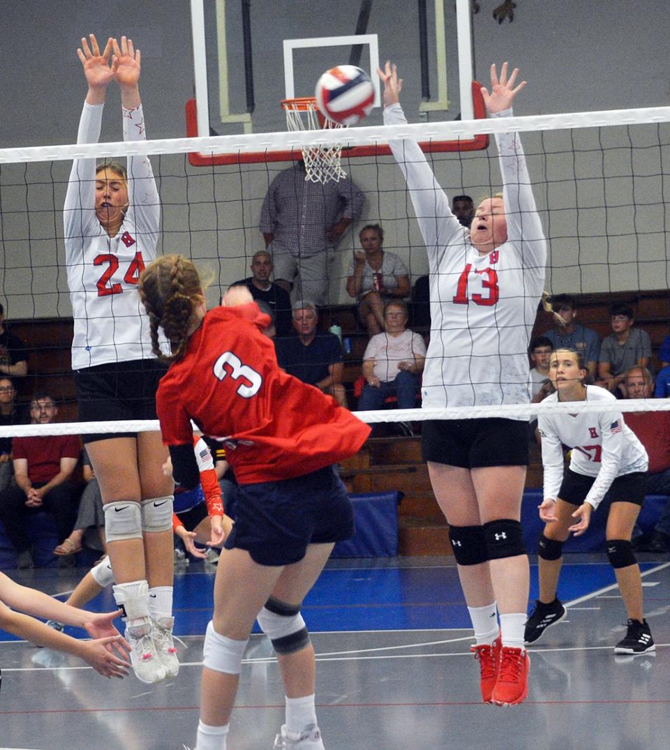 Heritage's Ava Poe (24) and Sophie Faith (13) put up a double block against Grace's Emma Smith (3) during a match on Sept. 8, 2022.