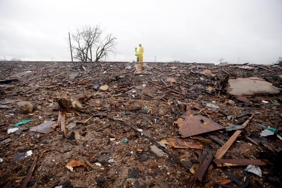 Firefighters stand on a rail line and examine the remains of the fertilizer plant that was the source of the blast. At least one witness said the berm of the railway line helped avert even more damage on the other side.