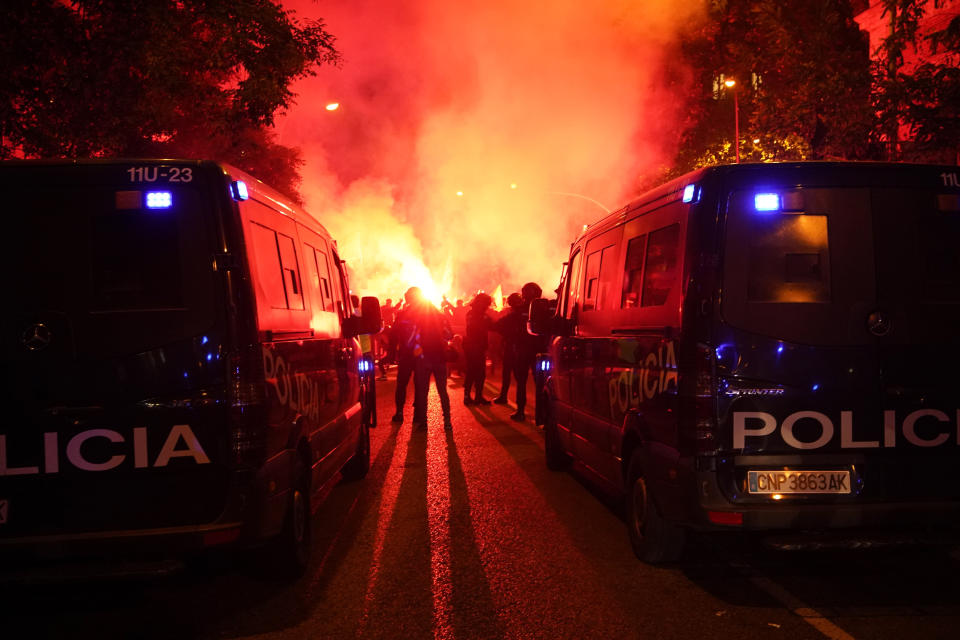 Demonstrators hold up flares next to the police officers during a protest against the amnesty at the headquarters of Socialist party in Madrid, Spain, Thursday, Nov. 16, 2023. Spain's acting Socialist prime minister, Pedro Sánchez, has been chosen by a majority of legislators to form a new leftist coalition government in a parliamentary vote. The vote came after nearly two days of debate among party leaders that centered almost entirely on a highly controversial amnesty deal for Catalonia's separatists that Sánchez agreed to in return for vital support to get elected prime minister again. (AP Photo/Andrea Comas)