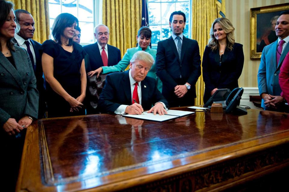 PHOTO: President Donald Trump signs an executive order in the Oval Office of the White House surrounded by small business leaders January 30, 2017 in Washington, DC. (Andrew Harrer/Getty Images)