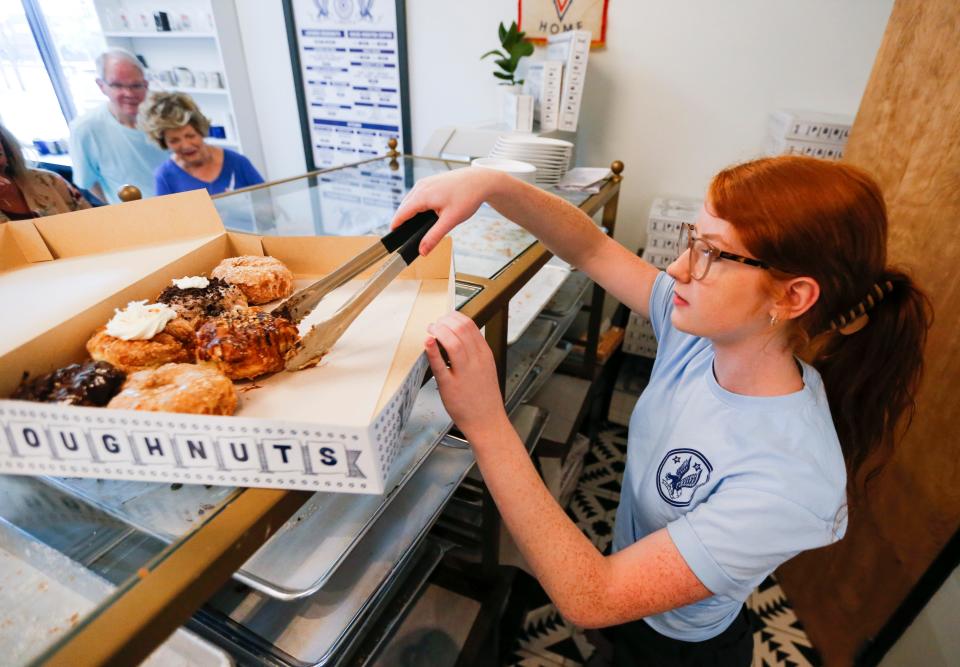 Parlor Doughnuts employee Halle Needham fills a to-go box with doughnuts on Thursday, June 1, 2023.