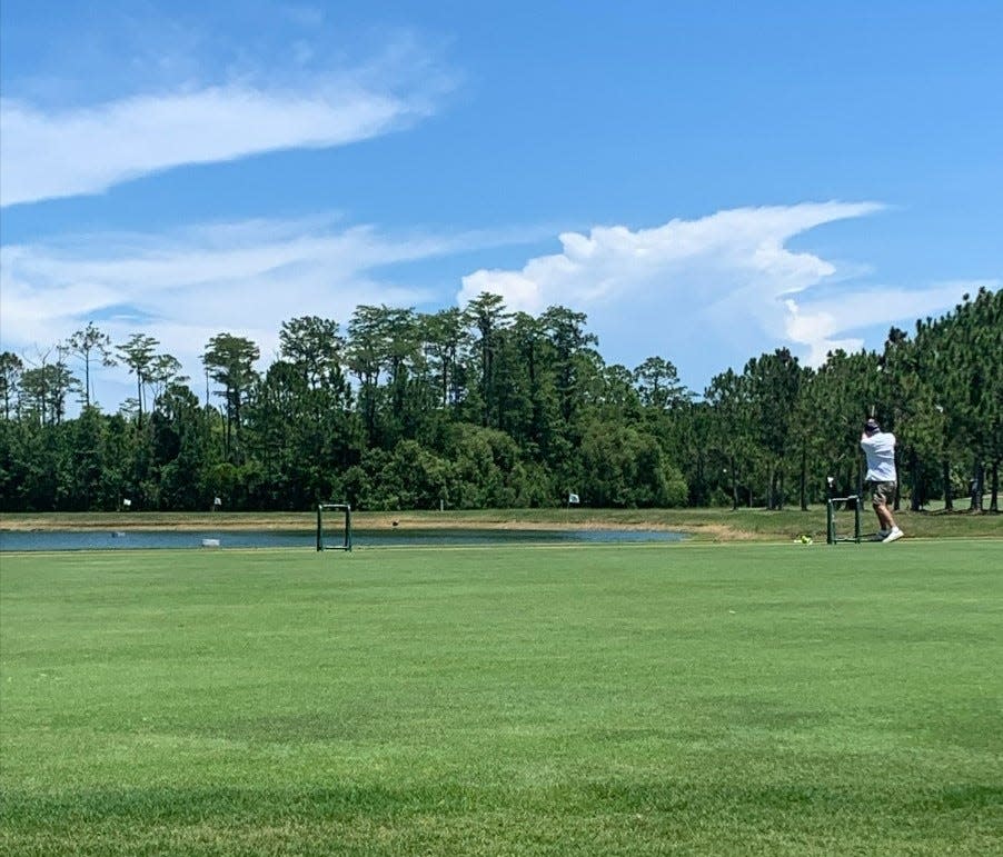 Golfers at the Grand Reserve Golf Club range warm up by hitting balls in a lake, with floating yardage markers.