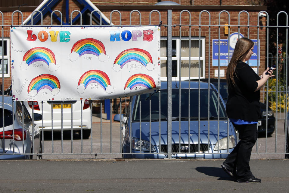 A woman walks past a rainbow banner on a school fence as the UK continues in lockdown to help curb the spread of coronavirus.