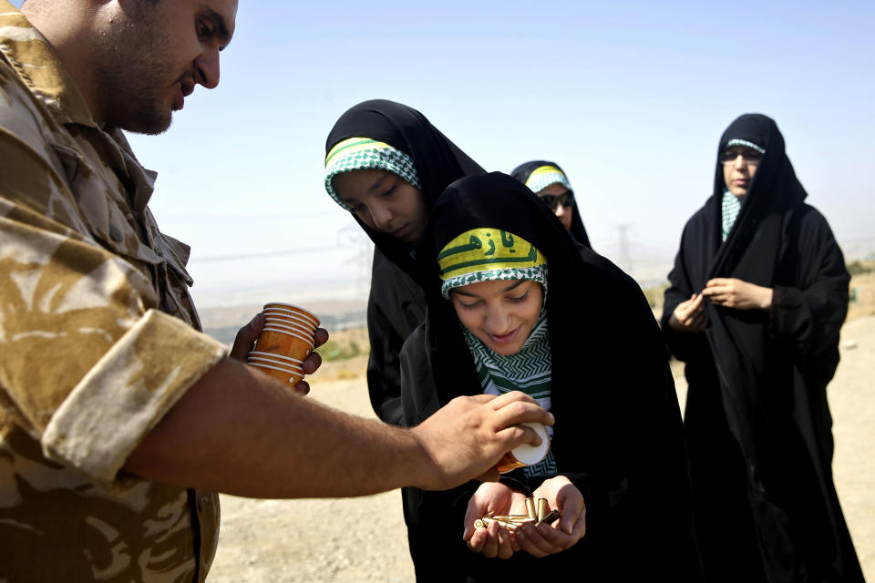 In this Thursday, Aug. 22, 2013 photo, a female member of the Basij paramilitary militia receives bullets during a training session in Tehran, Iran. Authorities created the Basij, which means mobilization in Persian, just after the country’s 1979 Islamic Republic. It is part of Iran’s powerful Revolutionary Guard. (AP Photo/Ebrahim Noroozi)