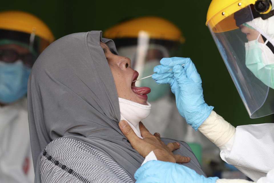 Health workers collect nasal swab samples from a woman during a mass test for the new coronavirus at a market in Jakarta, Indonesia, Thursday, June 25, 2020. (AP Photo/Tatan Syuflana)