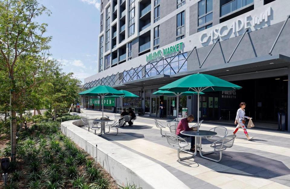 Cafe tables for a Milam’s Market grocer occupy a new public plaza at the base of the recently opened Cascade apartment tower at the Douglas Road Metrorail Station, the hub of an emerging urban neighborhood centered around walkability and transit.