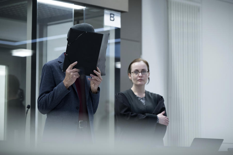 An 80-year-old former officer with communist East Germany's secret police, the Stasi, holds a folder in front of his face at the start of his trial at the state court in Berlin, Thursday March 14, 2024. The former officer went on trial Thursday over the killing of a Polish man at a border crossing in divided Berlin 50 years ago. (Sebastian Christoph Gollnow/dpa via AP)