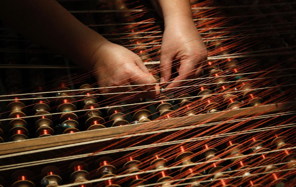 In this picture taken on Wednesday, May 13, 2020, a woman works at the Bevilacqua textiles in Venice, Italy. Venetians are rethinking their city in the quiet brought by the coronavirus pandemic. For years, the unbridled success of Venice's tourism industry threatened to ruin the things that made it an attractive destination to begin with. Now the pandemic has ground to a halt Italy’s most-visited city, stopped the flow of 3 billion euros in annual tourism-related revenue and devastated the city's economy. (AP Photo/Antonio Calanni)