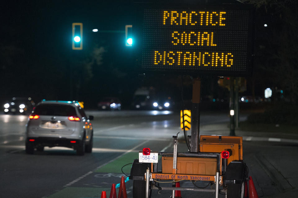 In this Wednesday, March 18, 2020 file photo, a sign reminding people about "social distancing" in the midst of the COVID-19 coronavirus outbreak stands next to a roadway in North Vancouver, British Columbia, Canada. Many see “social distancing” to be the greatest pandemic-era addition the vernacular yet — easily understood phrasing that’s helped communicate to millions that they need to keep a safe berth to avoid spreading the virus. (Jonathan Hayward/The Canadian Press via AP)