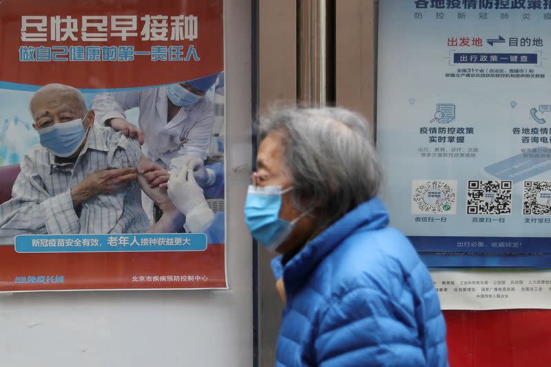 FILE PHOTO: A person walks past a poster encouraging elderly people to get vaccinated against COVID-19, in Beijing