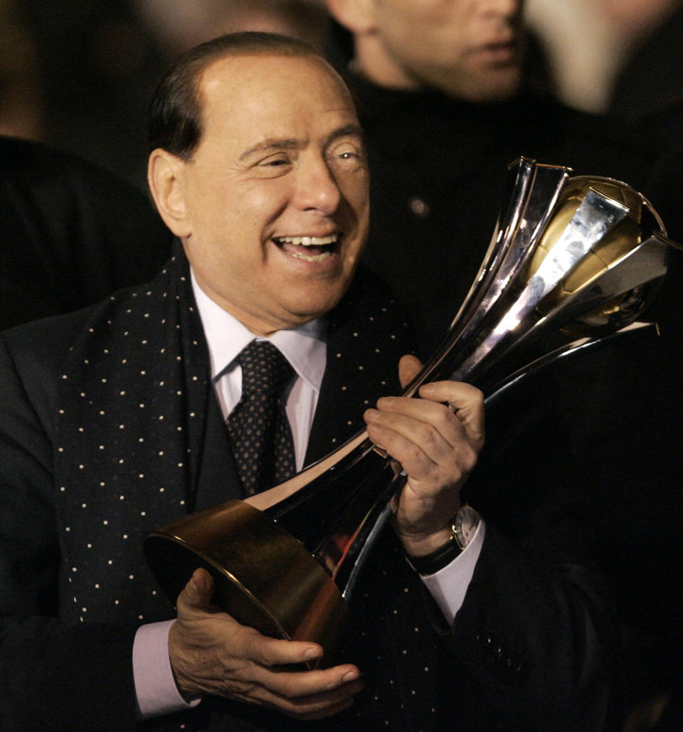 FILE - AC Milan's President Silvio Berlusconi holds the FIFA Club World Cup soccer championship trophy upon arrival at Milan's Malpensa airport, Italy, on Dec. 17, 2007. Berlusconi, the boastful billionaire media mogul who was Italy's longest-serving premier despite scandals over his sex-fueled parties and allegations of corruption, died, according to Italian media. He was 86. (AP Photo/Antonio Calanni, File)