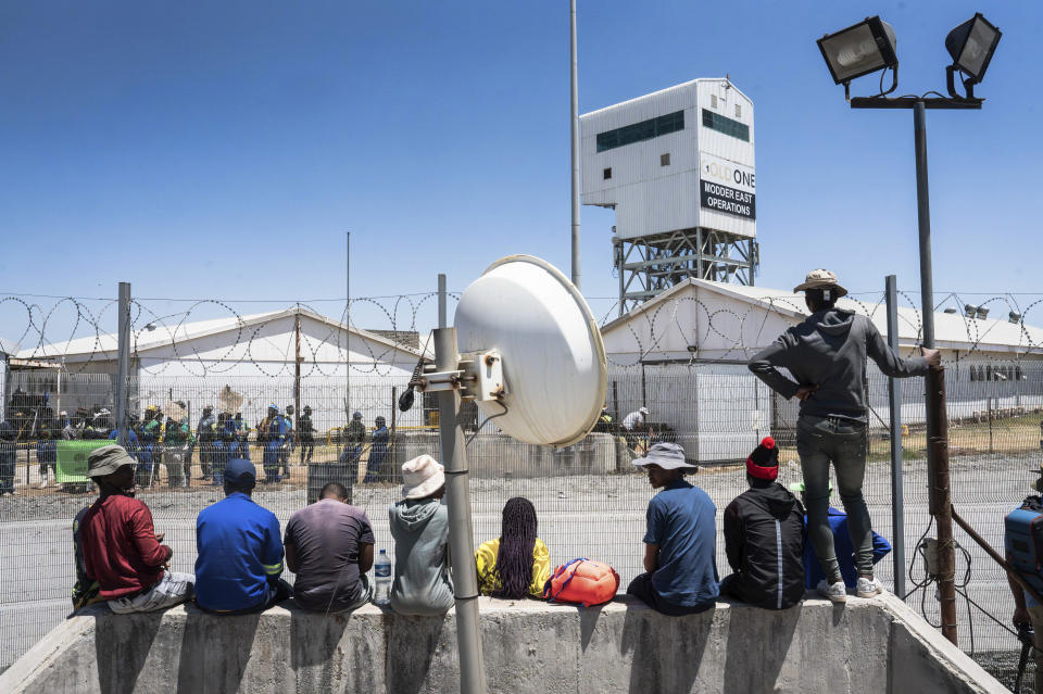 Fellow mineworkers look over the entrance of a goldmine in Springs, near Johannesburg, South Africa Wednesday, Oct. 25, 2025. A company official says more than 100 miners have escaped from the mine after being held underground for three days by fellow employees in a union dispute. (AP Photo)