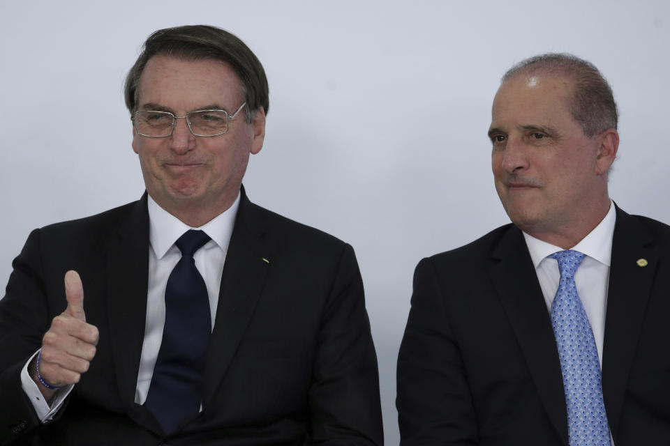 Brazil's President Jair Bolsonaro, left, gives a thumbs up sign as he stands next to his Chief of Staff Onyx Lorenzoni, during ceremony at the Planalto Presidential Palace in Brasilia, Brazil, Monday, March 25, 2019. Brazil's president says he is "open to dialogue" about an ambitious pension reform that has become a central pillar of his administration's agenda. (AP Photo/Eraldo Peres)