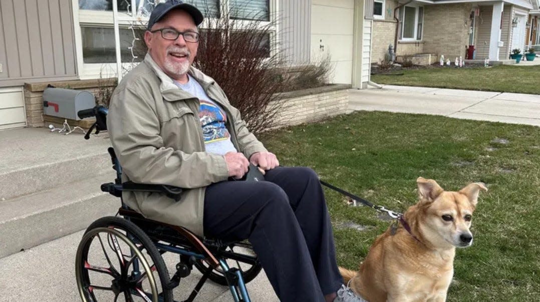 Mike Hoover smiles with his dog Daisy outside his home.