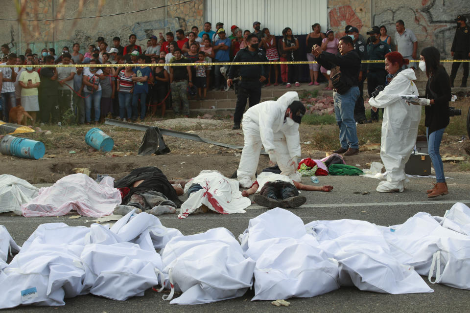 Bodies in bodybags are placed on the side of the road after an accident in Tuxtla Gutierrez, Chiapas state, Mexico, Dec. 9, 2021. Mexican authorities say at least 49 people were killed and dozens more injured when a cargo truck carrying Central American migrants rolled over on a highway in southern Mexico. (AP Photo )