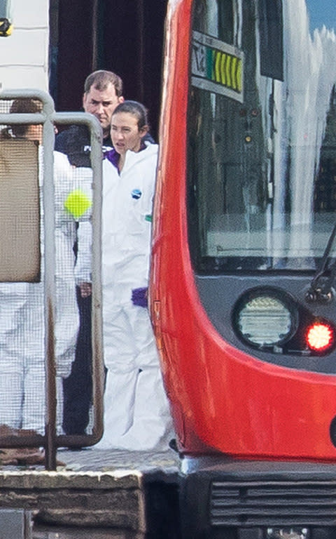  Forensics officers can be seen next to the evacuated tube train at Parsons Green Station  - Credit:  Peter Macdiarmid/LNP