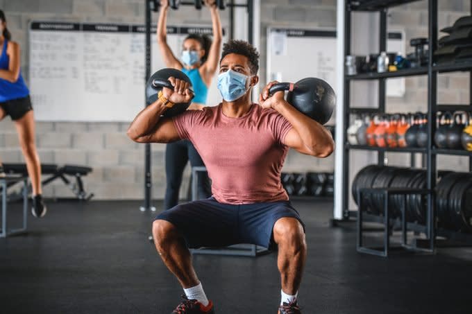 Masked Athlete Doing 2-Kettlebell Front Squat in Gym