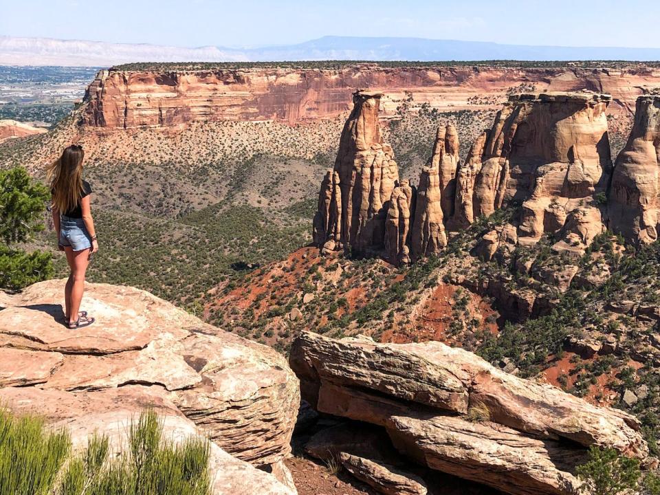 Emily stands on a huge rock looking out at a canyon with rock formations.