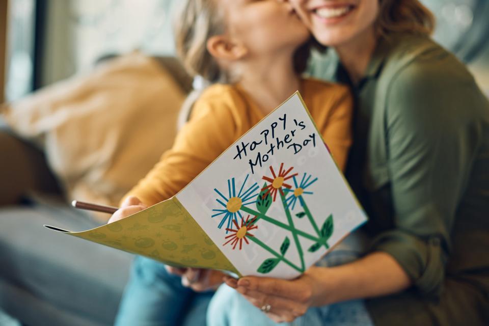 Close-up of woman receiving greeting card from her daughter on Mother's day.