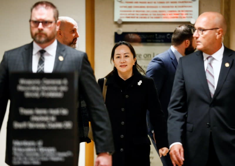 Huawei Chief Financial Officer Meng Wanzhou walks with a security team as she leaves B.C. Supreme Court for a lunch break during the first day of her extradition hearing in Vancouver