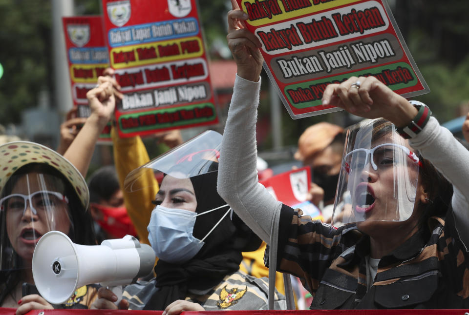 Entertainment workers wearing face shields as the precaution against coronavirus outbreak, take part in a protest against the large-scale restrictions imposed by the city government that requires the temporary closure of entertainment places, outside the city hall in Jakarta, Indonesia, Monday, Oct. 5, 2020.(AP Photo/Achmad Ibrahim)