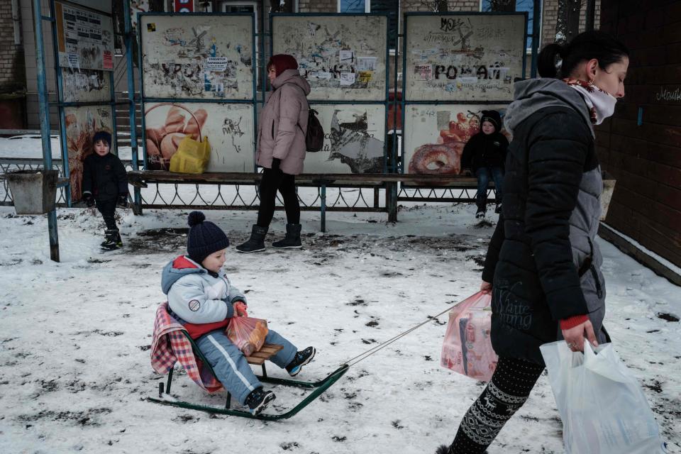 Inessa (L), 27, pulls her three-year-old son Alex on a sledge, after receiving food at the Ark of Salvation Church in Kramatorsk on February 12 (AFP via Getty Images)