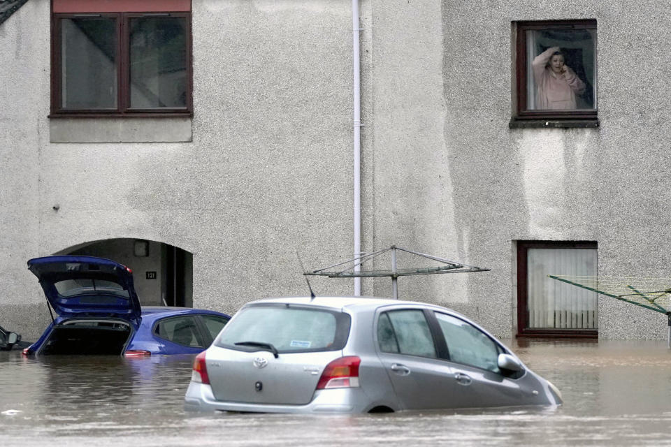 A woman talks on the phone as she looks out of a window onto the flooded property below, in Brechin, Scotland, Friday Oct. 20, 2023. The gale-force winds are expected to hit hardest the eastern part of Denmark's Jutland peninsula and the Danish islands in the Baltic Sea. But the British Isles, southern Sweden, northern Germany and parts of Norway also on the path of the storm, named Babet by U.K.’s weather forecaster, the Met Office. (Andrew Milligan/PA Wire/PA via AP)