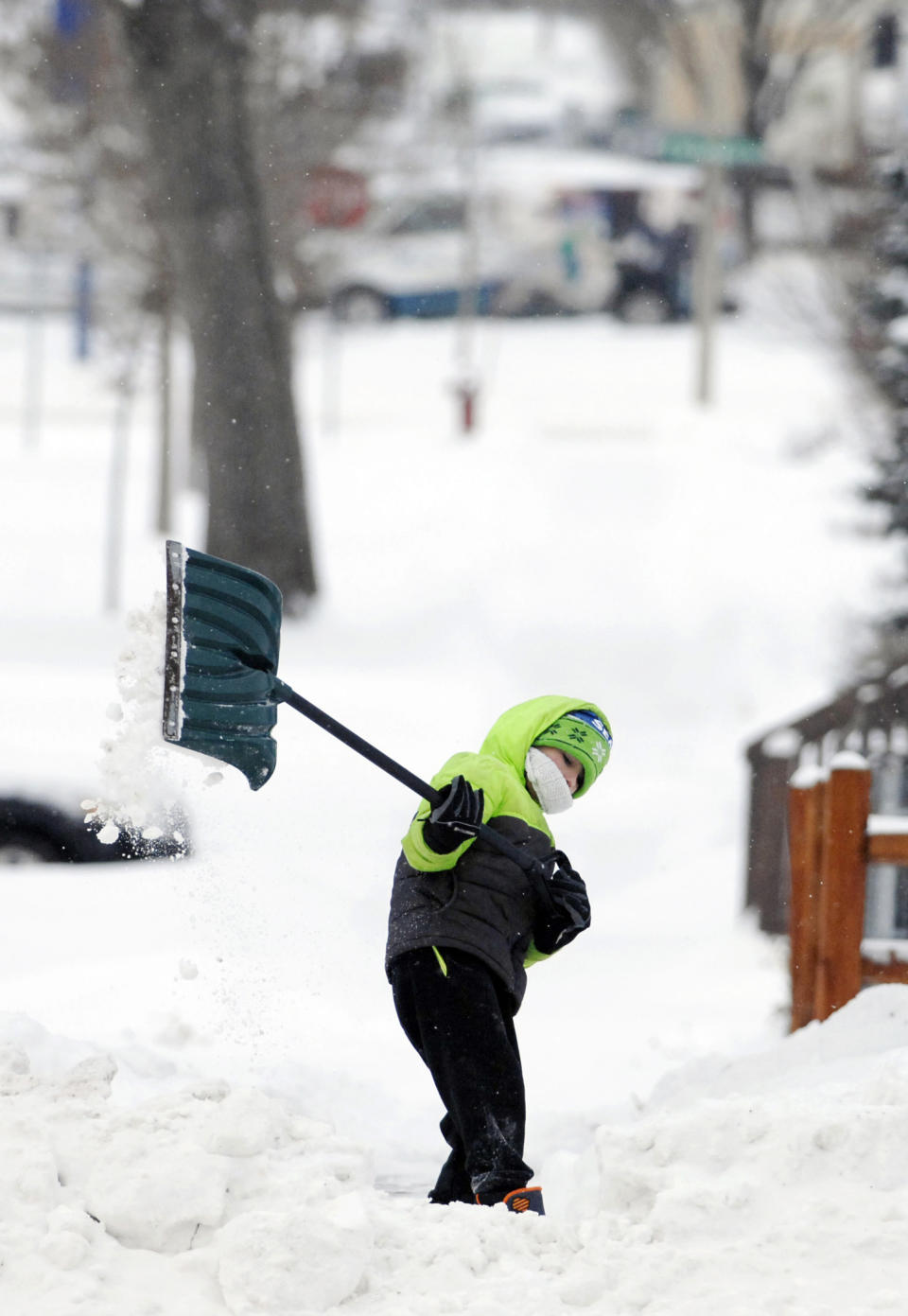 Vincent Schaff, 8, uses all of his body as he heaves a shovel full of snow from the sidewalk of his grandmother's home along Rosser Avenue Thursday, Dec. 27, 2018, in Bismarck, N.D. Forecasters posted a blizzard warning for parts of the Dakotas and Minnesota as a major winter storm delivered heavy snow and gusty winds to the region. (Mike McCleary/The Bismarck Tribune via AP)