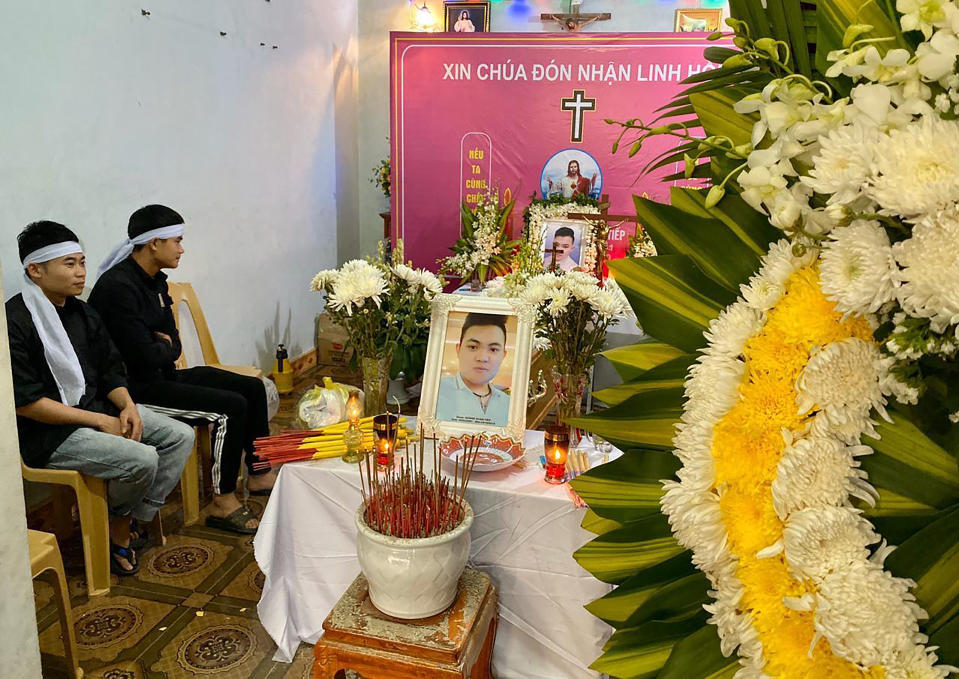 Relatives sit next to the shrine and coffin of Hoang Van Tiep at the family home ahead of his funeral on Thursday, Nov. 28, 2019 in Dien Chau, Vietnam. The 18-year old Tiep was among the 39 Vietnamese who died when human traffickers carried them by truck to England in October, and whose remains were among the 16 repatriated to their homeland Wednesday. (AP Photo/Hau Dinh)