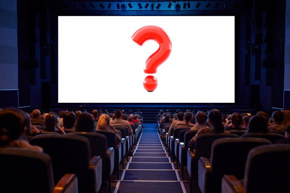 A packed movie theater with a red question mark filling the silver screen.