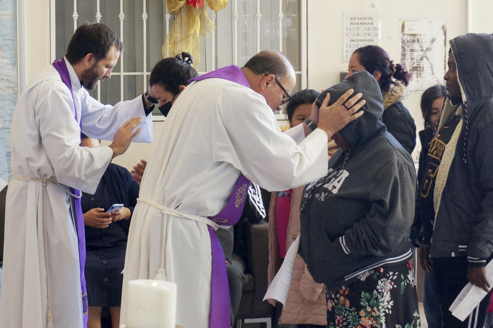 The Rev. Brian Strassburger, left, and the Rev. Flavio Bravo, right, bless migrants during Mass at the Casa del Migrant shelter in Reynosa, Mexico, on Dec. 15, 2022. Both hope and tension have been rising here and the few other shelters in this border city where thousands of migrants await news of U.S. border policy changes possibly less than a week away. (AP Photo/Giovanna Dell'Orto)