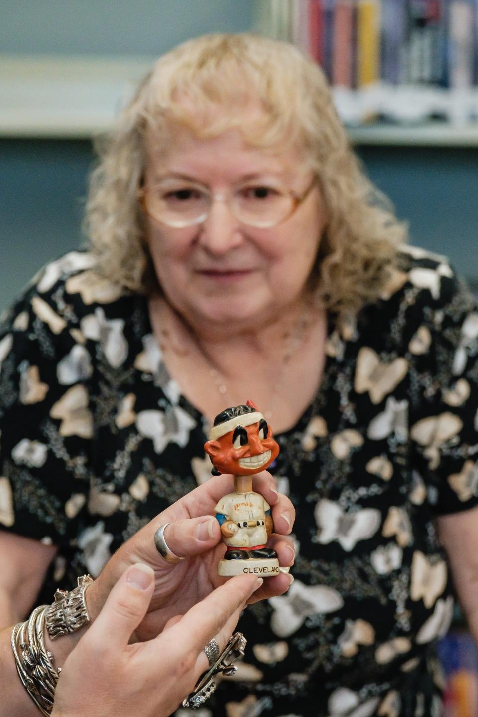 Denise Gilmore of Sugarcreek watches as Jason Adams appraises an antique Cleveland bobblehead Thursday at the New Philadelphia branch of the Tuscarawas County Library.
