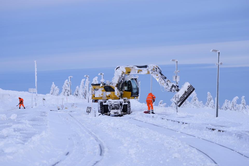 Railroad workers clear the tracks of snow on northern Germany's 1,142-meter (3,743 feet) highest mountain 'Brocken' at the Harz mountains near Schierke, Germany, Wednesday, Jan. 17, 2024. (AP Photo/Matthias Schrader)