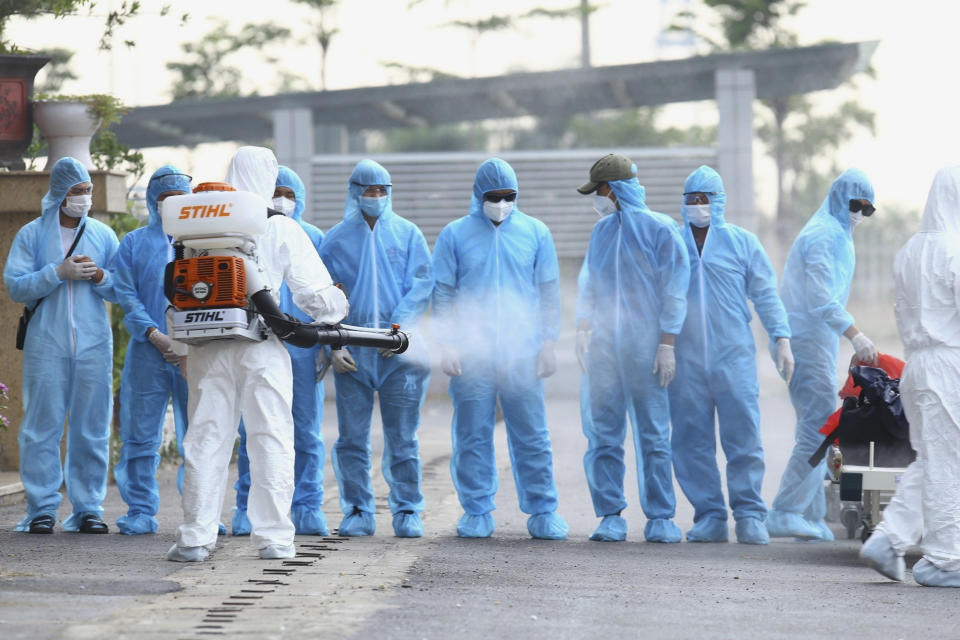 A health worker disinfects arriving Vietnamese COVID-19 patients at the national hospital of tropical diseases in Hanoi, Vietnam on Wednesday, July 29, 2020. The 129 patients who were working in Equatorial Guinea were brought home in a repatriation flight for treatment of the coronavirus. (Bui Cuong Quyet/VNA via AP)