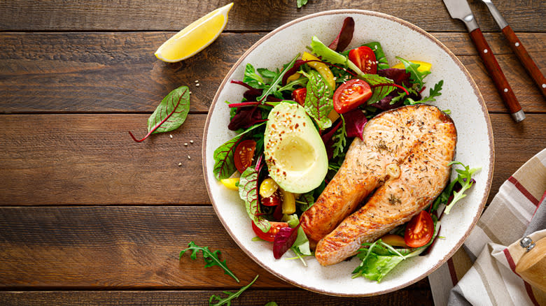 Salmon steak on salad with avocado