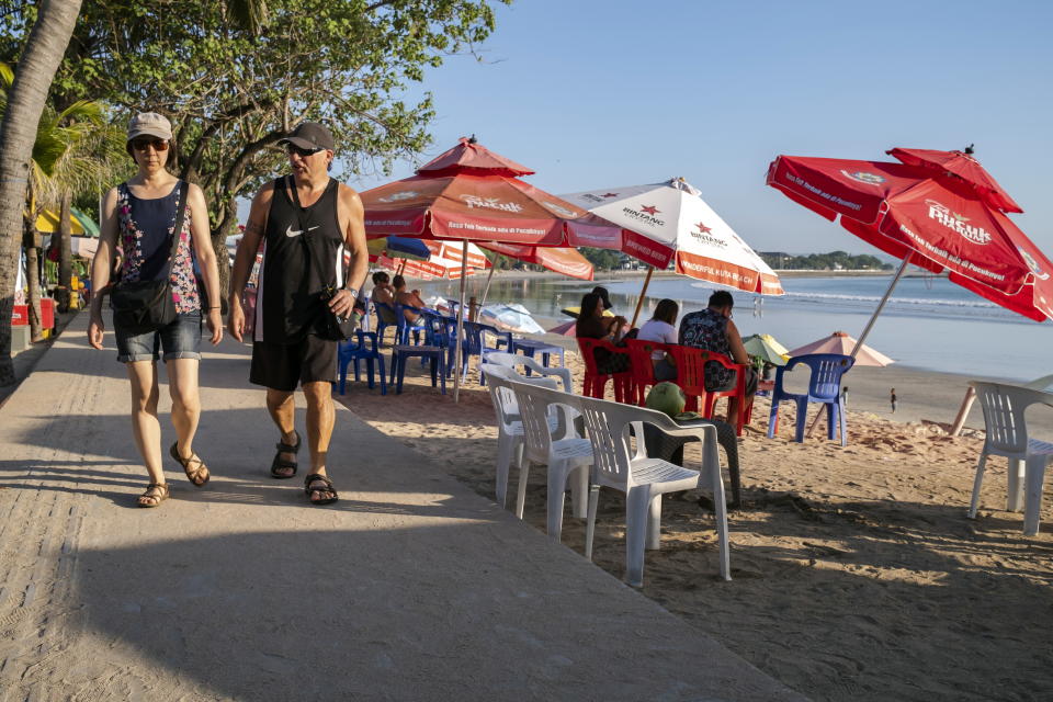 Foreign tourists walk at a beach in Kuta, Bali, Indonesia, 22 May 2023. 