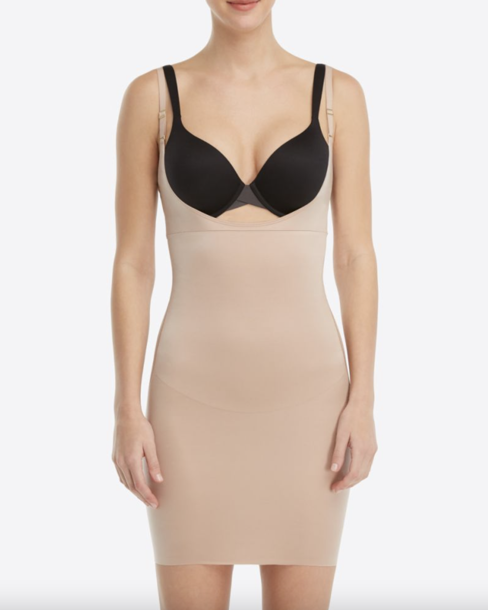 model wearing a black bra and beige Spanx SmartGrip Slips Open-Bust Full Slip in Foundation (Photo via Spanx)