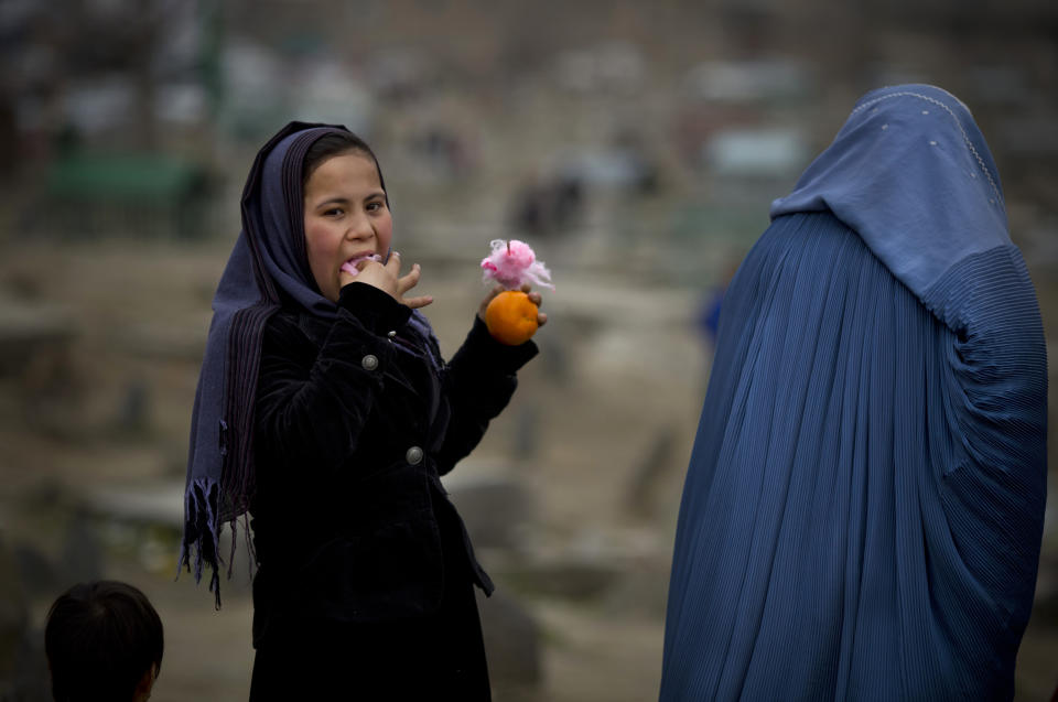 In this Friday, March 7, 2014 photo, an Afghan girl eats cotton candy as she visits with her mother a cemetery in the center of Kabul, Afghanistan. A gender and development specialist and human rights activist, Afghan Wazhma Frogh says her experience characterizes the women’s rights movement in her country- after 12 years, billions of dollars and countless words emanating from the West commiserating with Afghan women, the successes are fragile, the changes superficial and vulnerable. (AP Photo/Anja Niedringhaus)