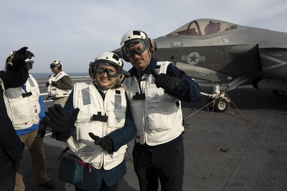 El ministro argentino de Defensa, Luis Petri, derecha, y la canciller Diana Mondino saludan al fotógrafo sobre la cubierta del portaaviones estadounidense USS George Washington en aguas de Argentina, el jueves 30 de mayo de 2024, durante ejercicios militares conjuntos entre ambos países. (AP Foto/Víctor R. Caivano)