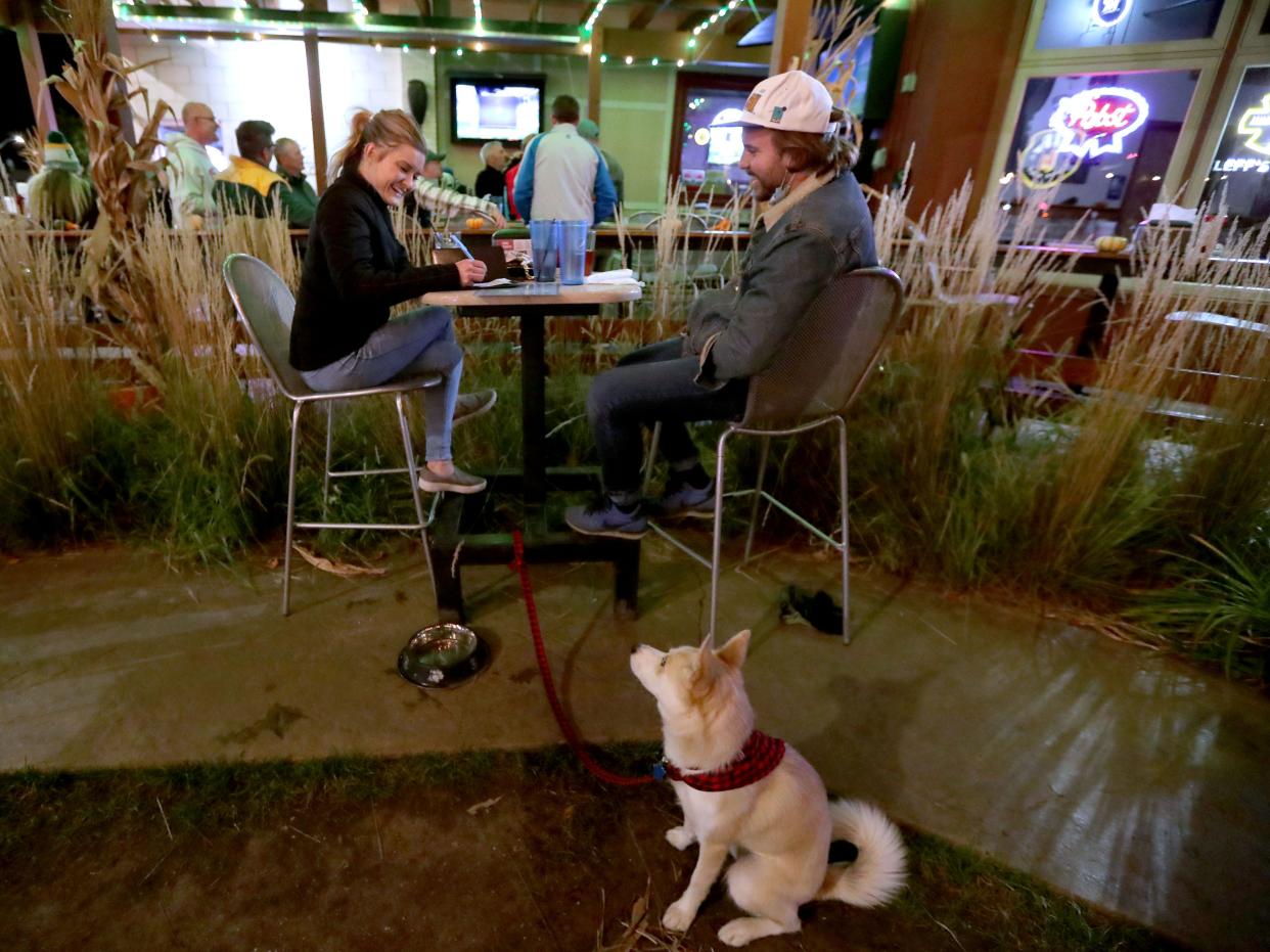 Marissa Kling, left, and Ben Kosmiter, with their dog, Finley sit in the outdoor dining area of Leff's Lucky Town on West State Street in Wauwatosa during the Green Bay Packers game against the Atlanta Falcons on Monday, Oct. 5, 2020.