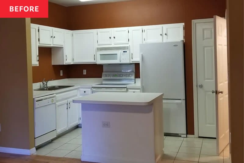 A kitchen with white cabinets, appliances and brown walls.